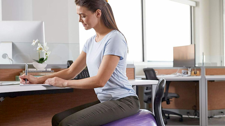 women with support back brace sitting on pilates ball