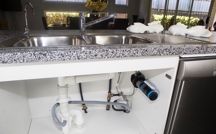 picture of an open concept kitchen with dining table, marble island with sink and under sink water filter