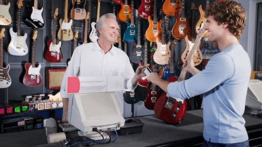 a young man buying guitar for sale in a music store